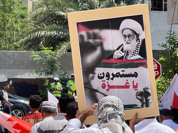 Protester holds a banner featuring a picture of Ayatollah Qassim and the slogan 